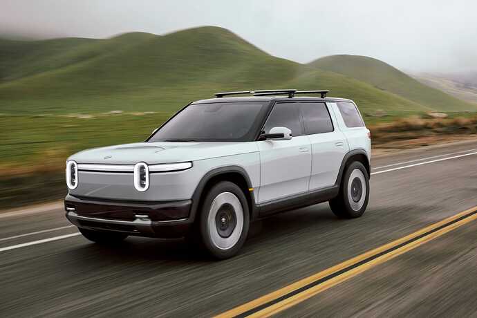 Rivian R2 driving past green hills